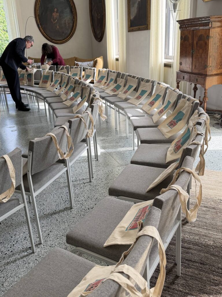 Borse con il segno di Italian Week 2026 sulle sedie della sala, prima della presentazione a Berlino